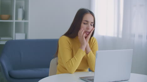 Toothache.-Close-up-upset-woman-at-workplace-uses-laptop-she-has-toothache-and-touches-her-face-with-her-hand.-Tooth-disease-concept